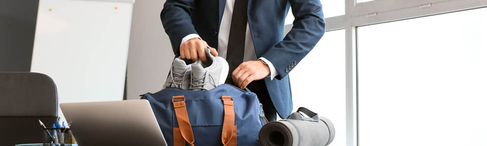 Young businessman in a suit putting his running shoes into his gym bag Young businessman in a suit putting his running shoes into his gym bag